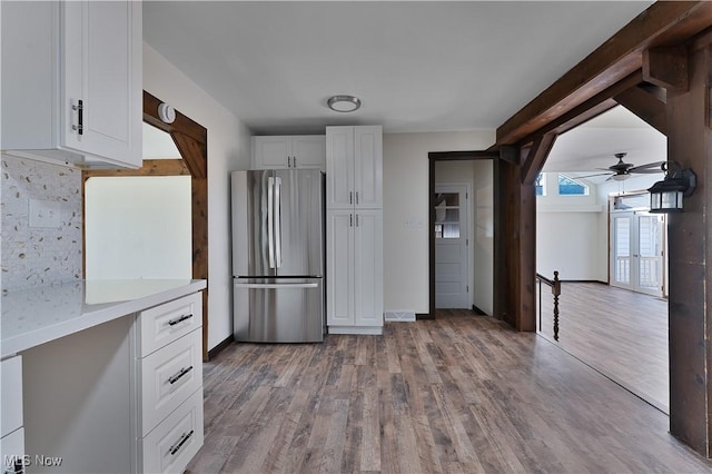 kitchen with hardwood / wood-style flooring, ceiling fan, stainless steel fridge, tasteful backsplash, and white cabinetry