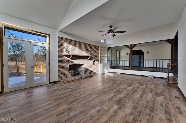 unfurnished living room featuring french doors, hardwood / wood-style flooring, a brick fireplace, and ceiling fan