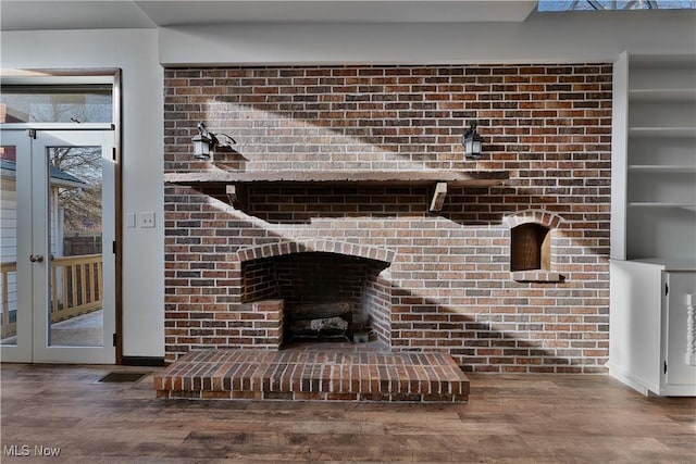 details featuring wood-type flooring, french doors, and a brick fireplace