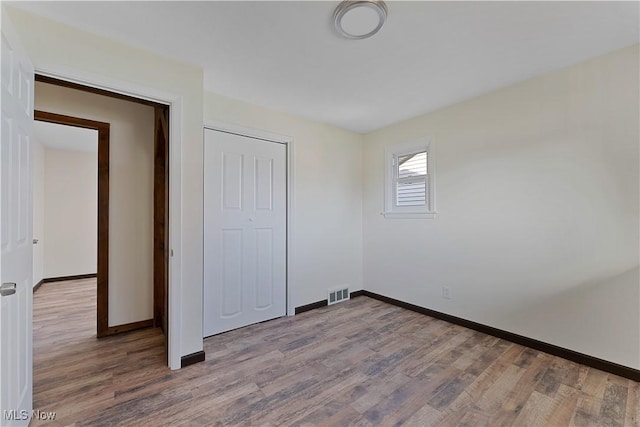 unfurnished bedroom featuring hardwood / wood-style floors and a closet