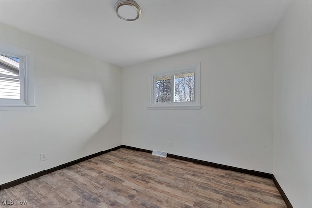 spare room with a healthy amount of sunlight and hardwood / wood-style flooring