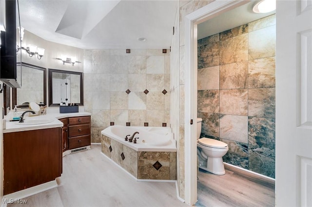 full bath featuring tile walls, toilet, wood finished floors, vanity, and a garden tub