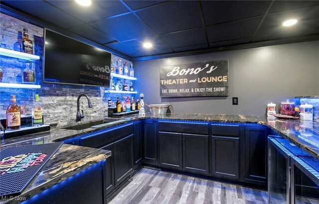 bar featuring backsplash, crown molding, sink, and light hardwood / wood-style flooring