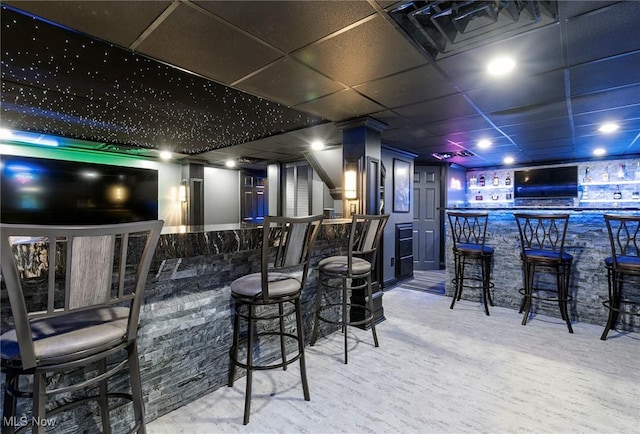 bar with a community bar, carpet flooring, and a drop ceiling