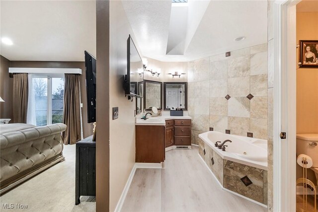 bathroom with vanity, wood-type flooring, tile walls, and tiled tub