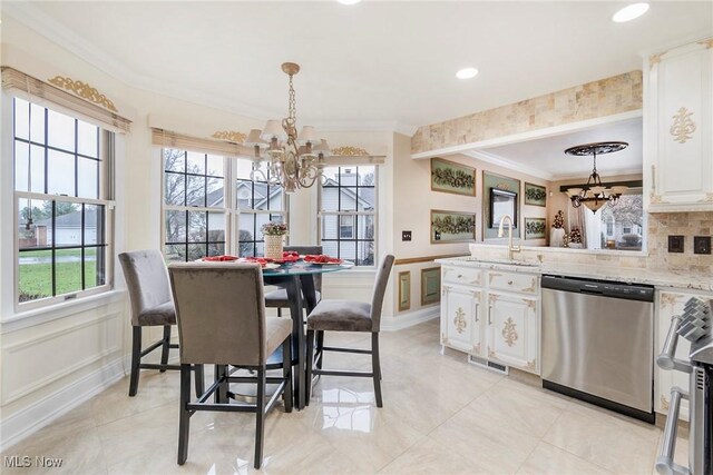 kitchen featuring sink, light stone counters, white cabinets, decorative light fixtures, and stainless steel dishwasher