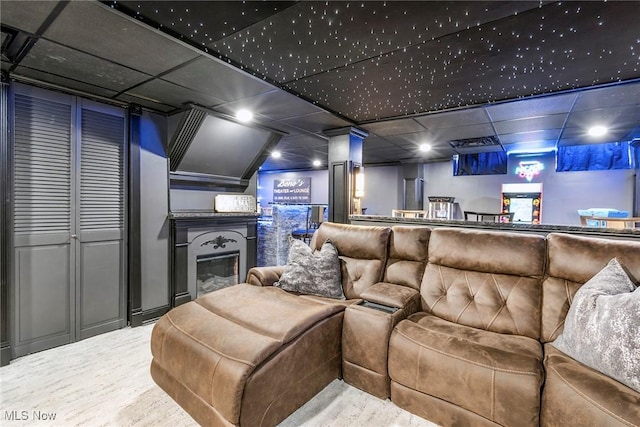 home theater with a glass covered fireplace and a paneled ceiling