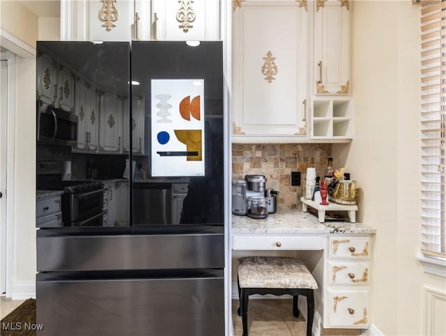 kitchen with light stone countertops, gas range, tasteful backsplash, and white cabinetry