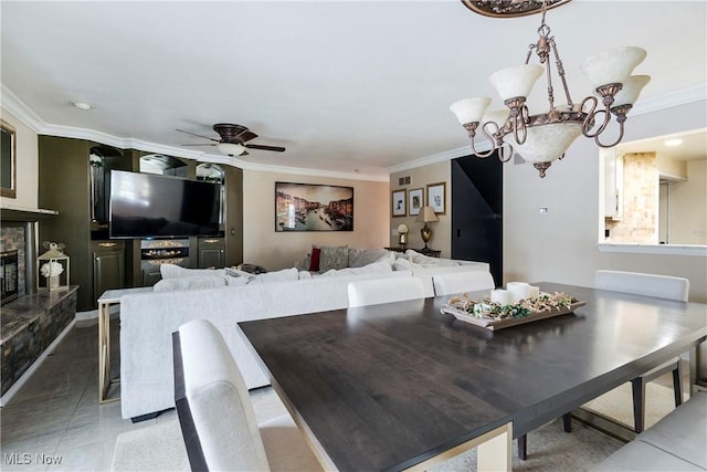 dining room with ceiling fan with notable chandelier, crown molding, and a fireplace