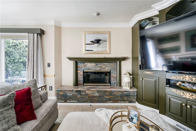 living room with a stone fireplace and crown molding