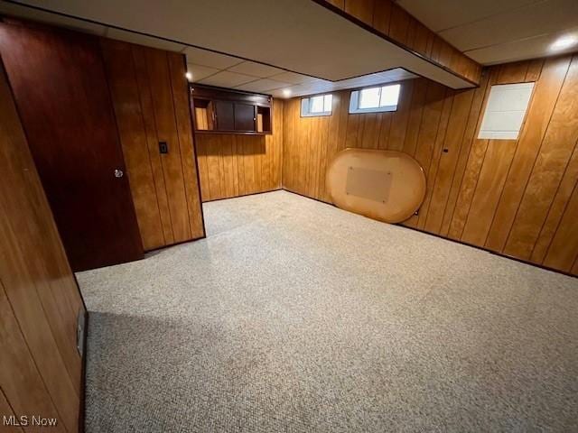 basement with wood walls and a drop ceiling