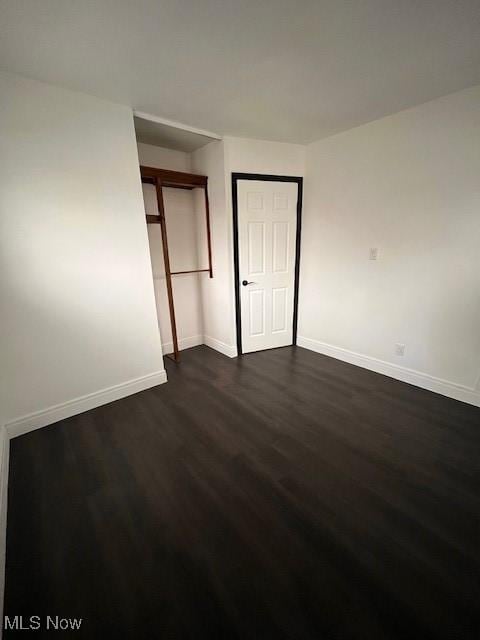 unfurnished bedroom featuring dark hardwood / wood-style flooring and a closet