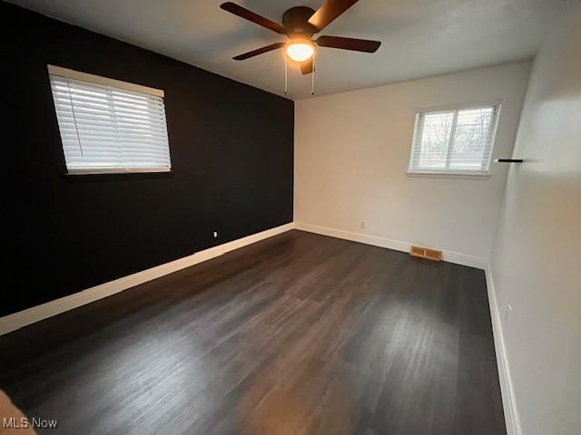 empty room with dark hardwood / wood-style flooring and ceiling fan