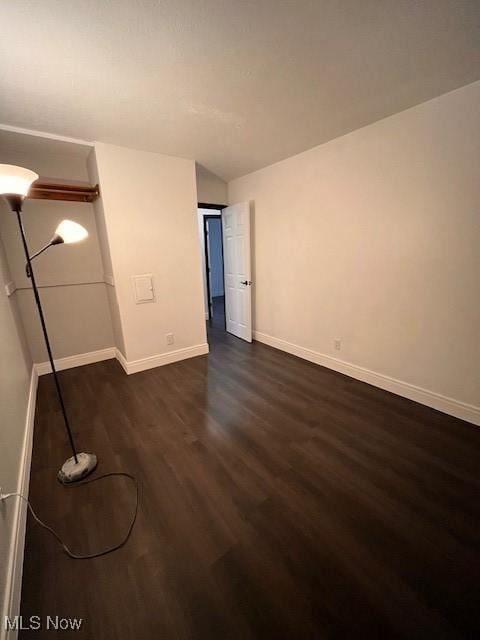 unfurnished bedroom with dark wood-type flooring and vaulted ceiling