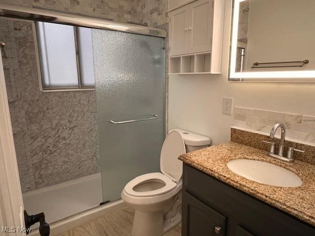 bathroom featuring vanity, toilet, and a shower with shower door