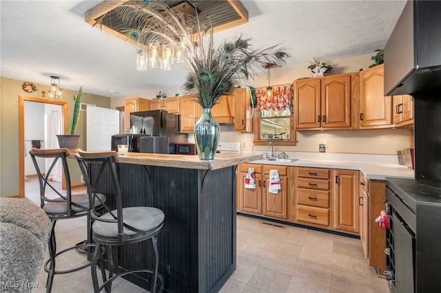 kitchen with a breakfast bar, black appliances, sink, a textured ceiling, and a kitchen island