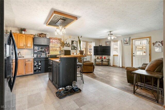 kitchen featuring stainless steel fridge, light wood-type flooring, a breakfast bar, ceiling fan, and a center island