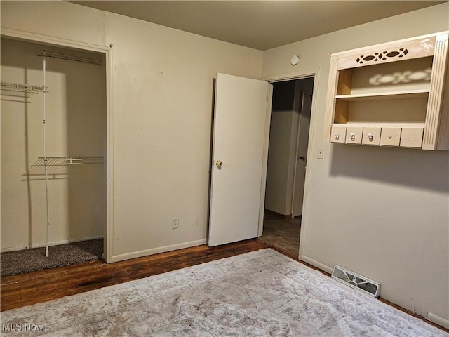 unfurnished bedroom with dark hardwood / wood-style floors and a closet