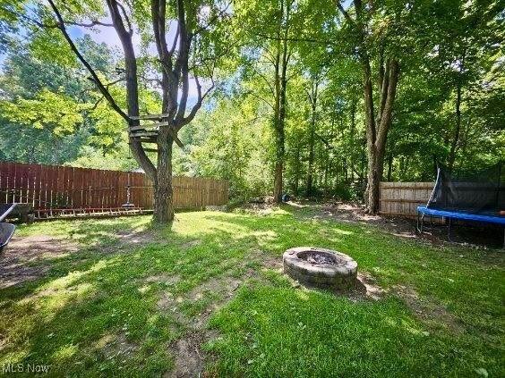 view of yard with an outdoor fire pit and a trampoline