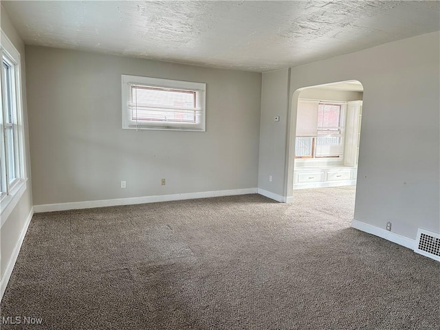 carpeted empty room featuring a textured ceiling