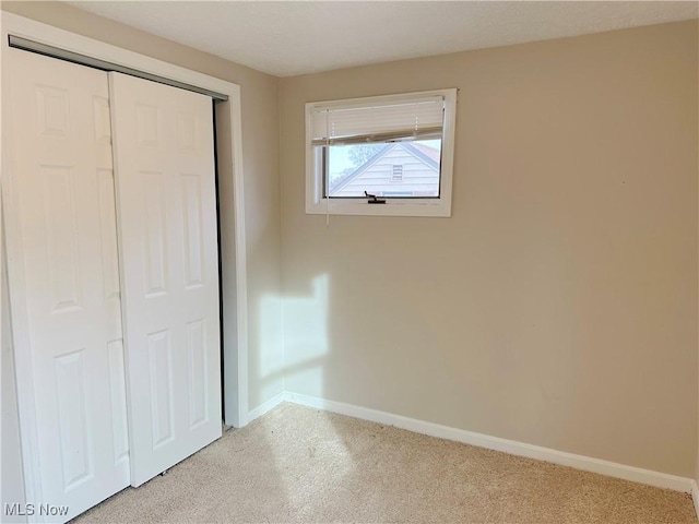 unfurnished bedroom with light carpet and a closet