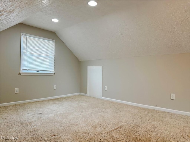 additional living space with carpet flooring, a textured ceiling, and vaulted ceiling