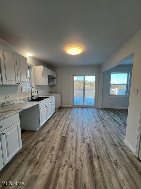 kitchen with white cabinetry, sink, and light hardwood / wood-style flooring