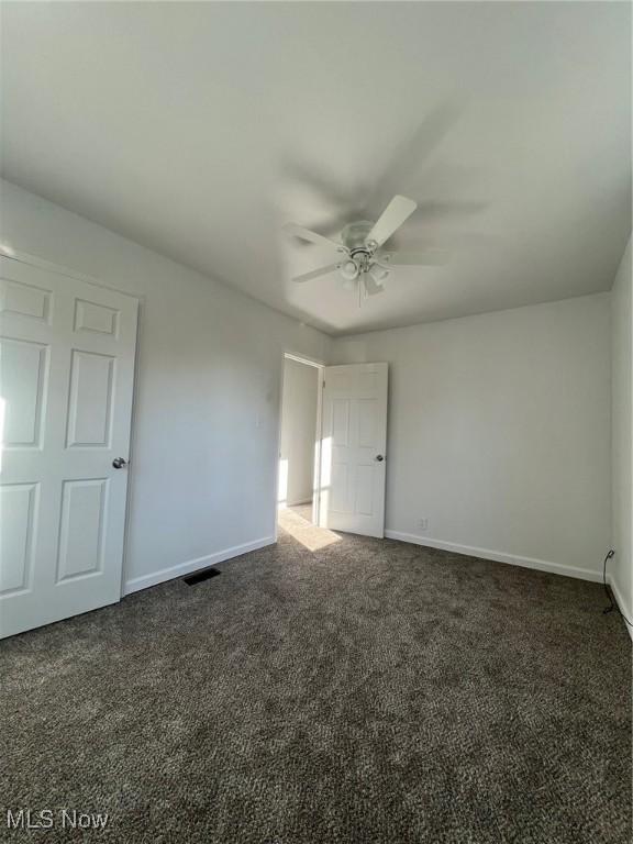 carpeted spare room with ceiling fan