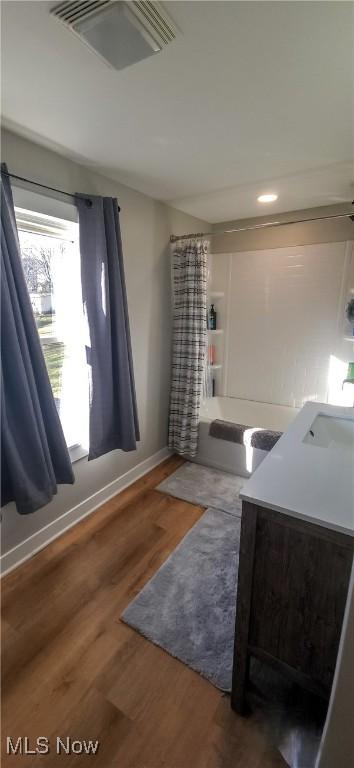 full bathroom featuring shower / bath combination with curtain, visible vents, a sink, wood finished floors, and baseboards