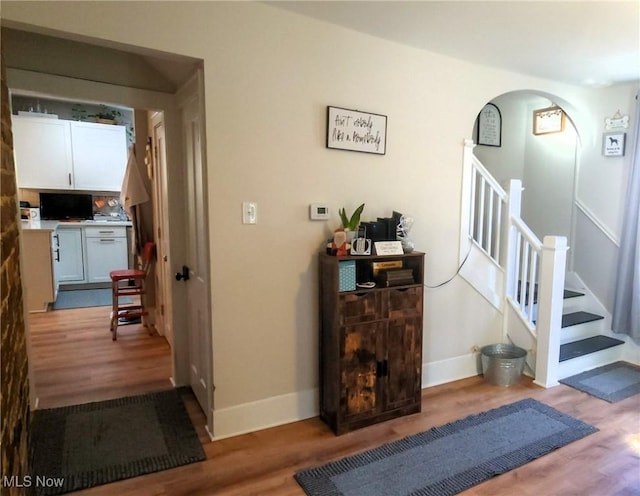 interior space featuring baseboards, stairway, and wood finished floors