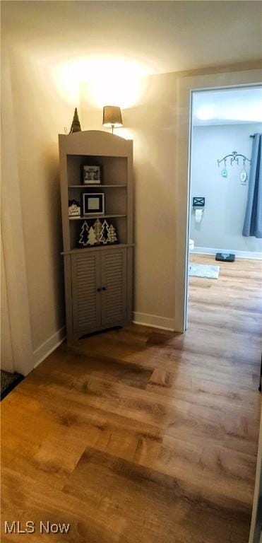 corridor with baseboards and wood finished floors