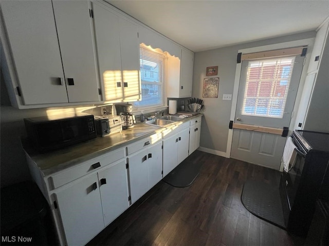 kitchen with sink, white cabinetry, dark wood-type flooring, and black appliances