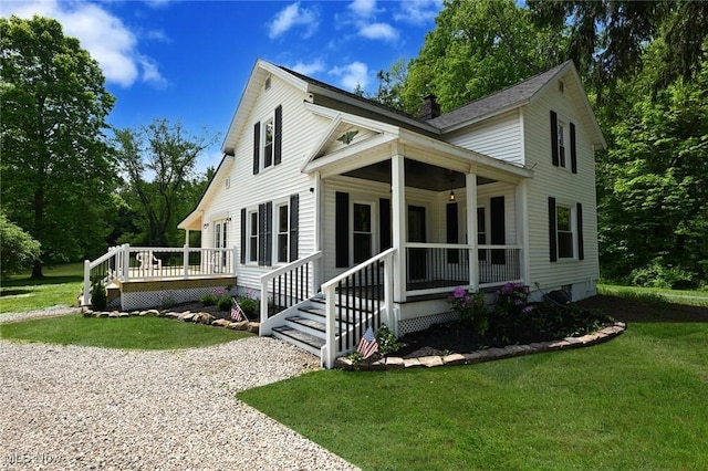 view of front facade featuring covered porch, a wooden deck, and a front yard