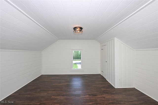 bonus room featuring wooden walls, dark hardwood / wood-style floors, and lofted ceiling