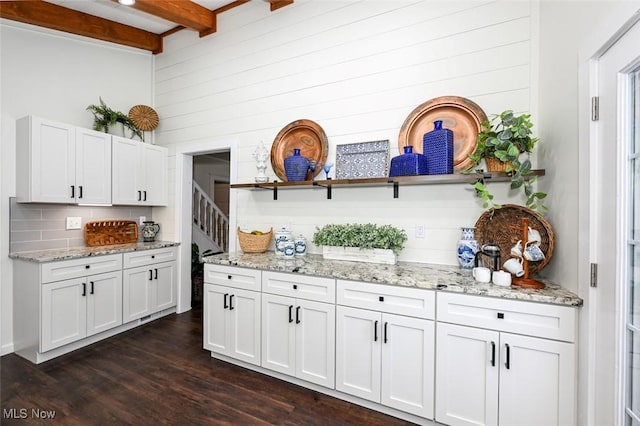 kitchen with wood walls, dark hardwood / wood-style flooring, white cabinets, and beamed ceiling