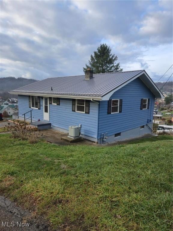 rear view of house featuring central AC unit and a lawn