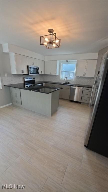 kitchen featuring white cabinets, sink, kitchen peninsula, stainless steel appliances, and a chandelier