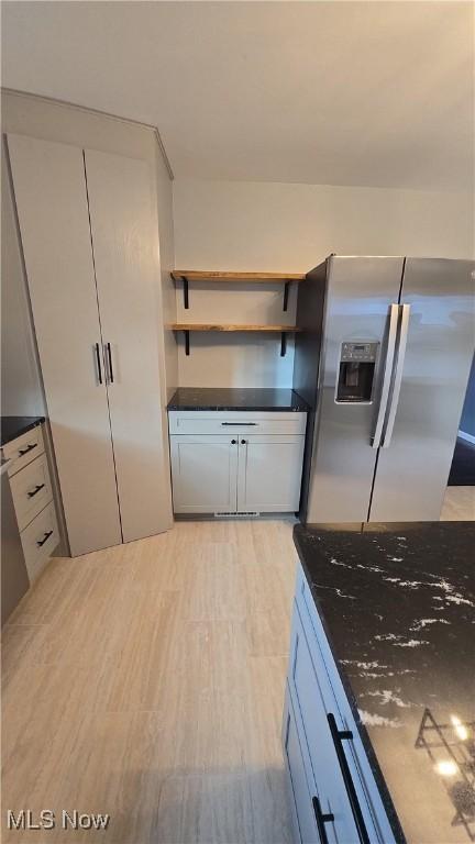 kitchen featuring stainless steel fridge with ice dispenser and dark stone countertops