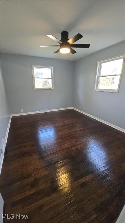 unfurnished room with ceiling fan and dark wood-type flooring