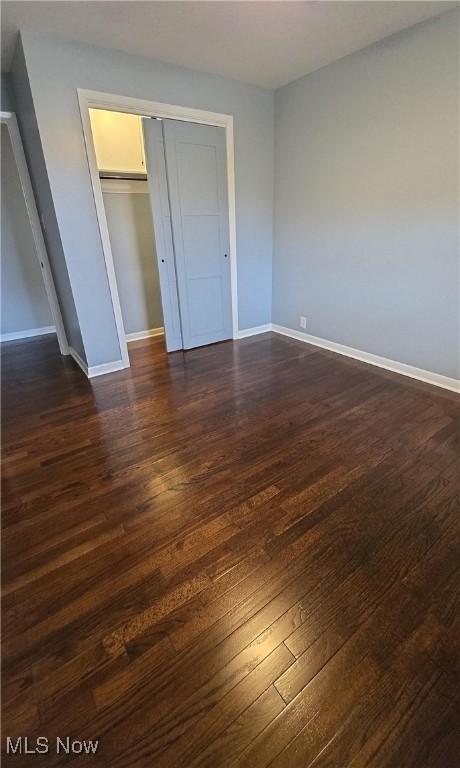 unfurnished bedroom with a closet and dark wood-type flooring