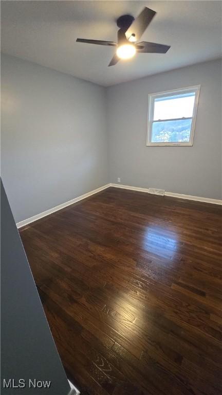 spare room with dark hardwood / wood-style flooring and ceiling fan