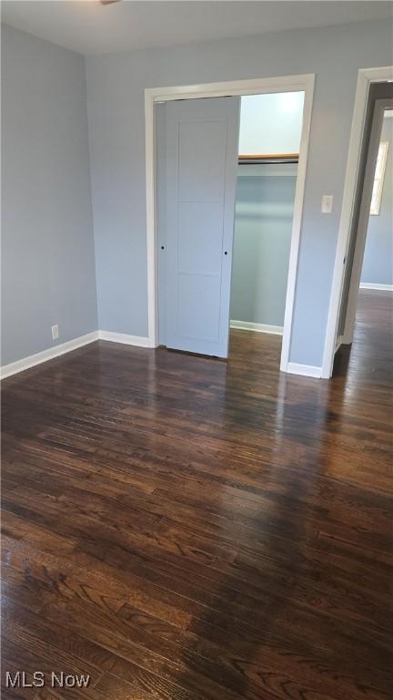 unfurnished bedroom with a closet and dark hardwood / wood-style flooring