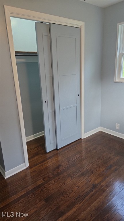 unfurnished bedroom featuring a closet and dark wood-type flooring