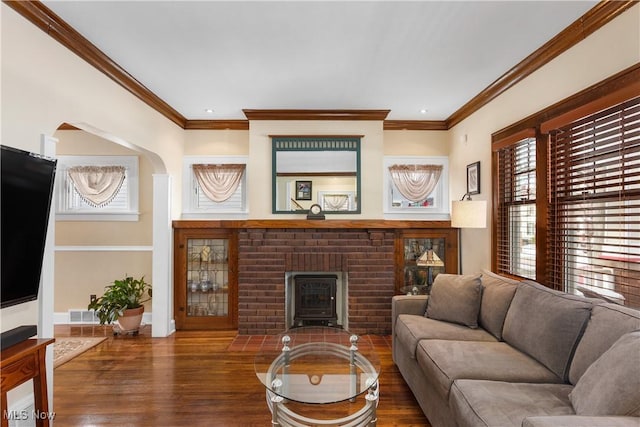 living room with crown molding, dark wood-type flooring, and a brick fireplace