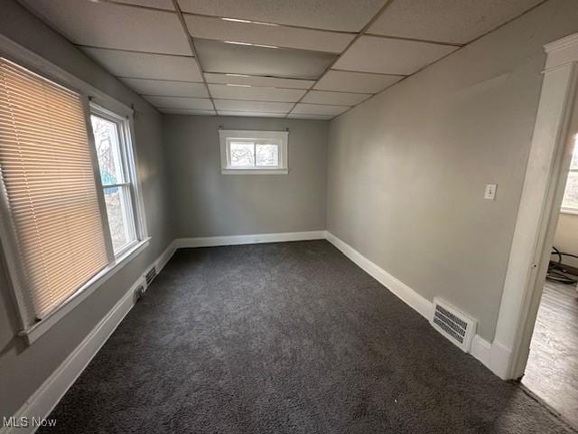 carpeted spare room with a drop ceiling