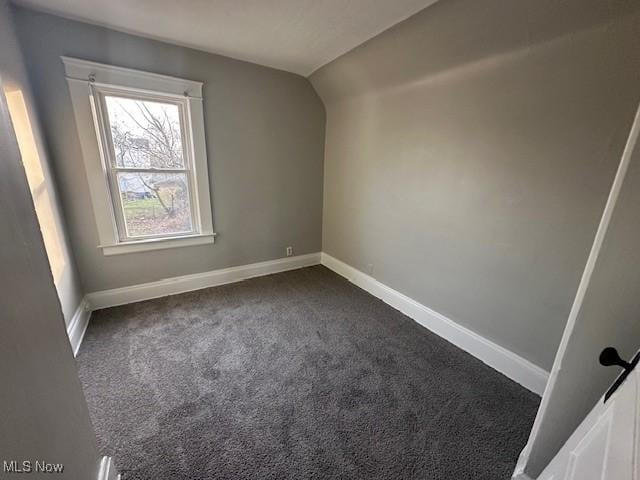 additional living space featuring dark colored carpet and lofted ceiling