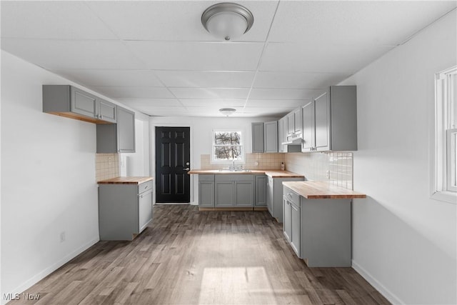 kitchen with butcher block counters, sink, gray cabinets, and light wood-type flooring