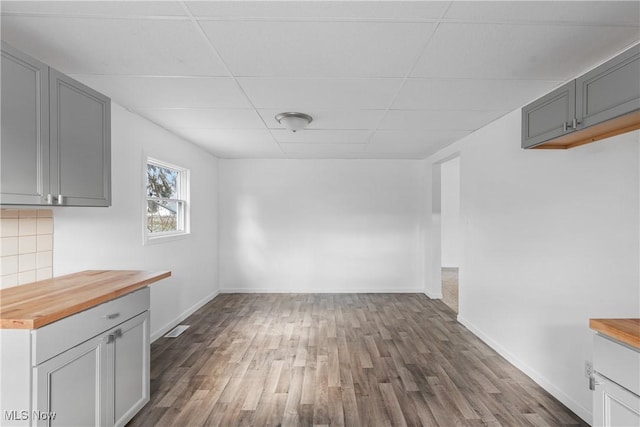 unfurnished dining area with dark hardwood / wood-style flooring and a drop ceiling