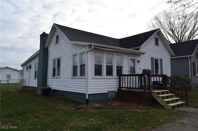 view of front of house with central AC and a front yard