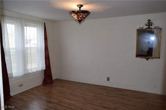 empty room featuring a wealth of natural light and dark wood-type flooring